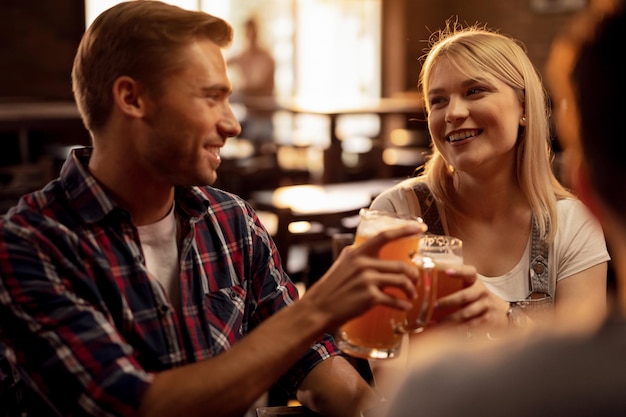 Jovem casal feliz brindando com cerveja e se divertindo em um bar