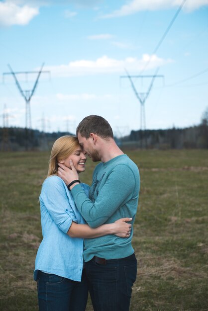 Jovem casal feliz caminhando, se abraçando e se beijando no campo