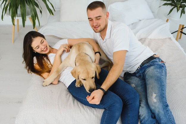 Jovem casal feliz com cachorro sentado em casa