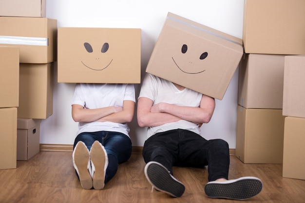 Jovem casal feliz com caixas de papelão nas cabeças.