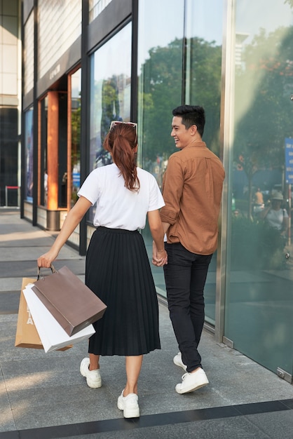 Jovem casal feliz com sacolas de compras na cidade se divertindo juntos