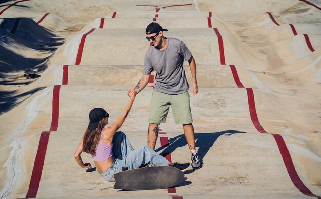 Jovem casal feliz com skates desfruta de longboard no skatepark