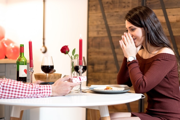 Jovem casal feliz comemorando o dia dos namorados com um jantar em casa bebendo vinho, felicidades.