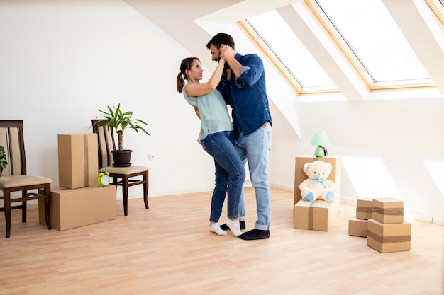 Jovem casal feliz dançando e comemorando a mudança para a nova casa.