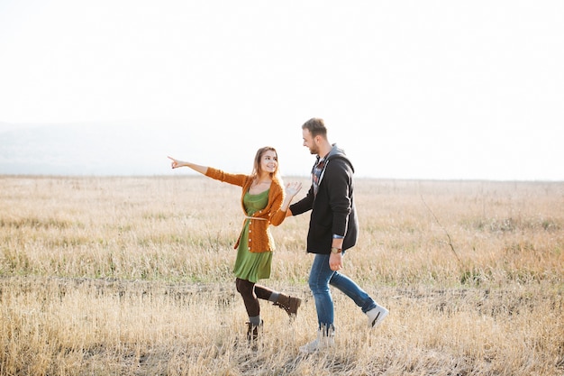 Jovem casal feliz de homem e mulher caminhando ao ar livre em um campo.