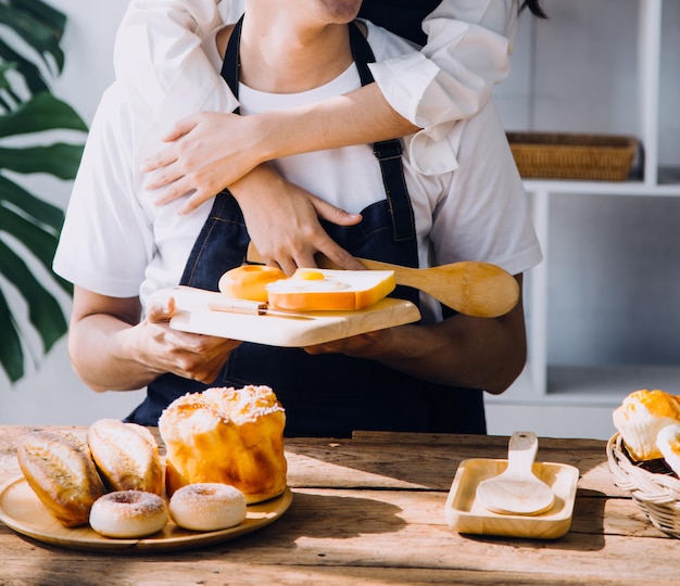 Jovem casal feliz está aproveitando e preparando uma refeição saudável em sua cozinha e lendo receitas no laptop