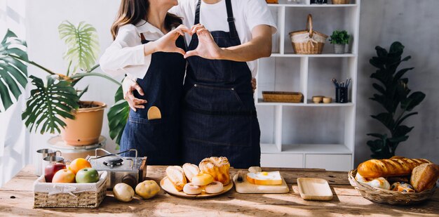 Jovem casal feliz está aproveitando e preparando uma refeição saudável em sua cozinha e lendo receitas no laptop