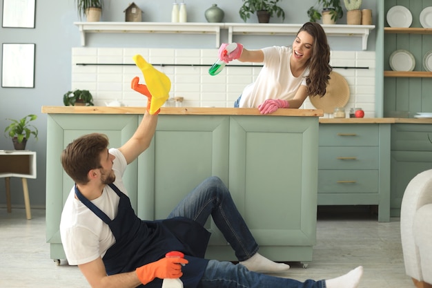 Foto jovem casal feliz está se divertindo ao fazer a limpeza em casa.