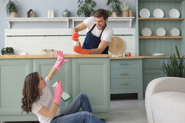 Foto jovem casal feliz está se divertindo ao fazer a limpeza em casa.