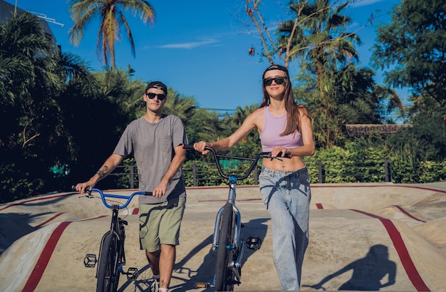 Jovem casal feliz gosta de andar de bmx no skatepark