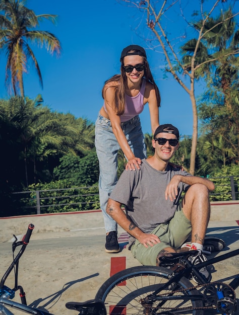 Jovem casal feliz gosta de andar de bmx no skatepark