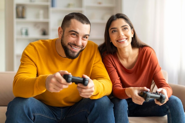 Jovem casal feliz jogando videogames com joysticks em casa