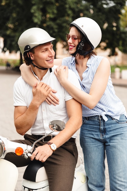 Jovem casal feliz juntos em uma moto na rua da cidade, rindo