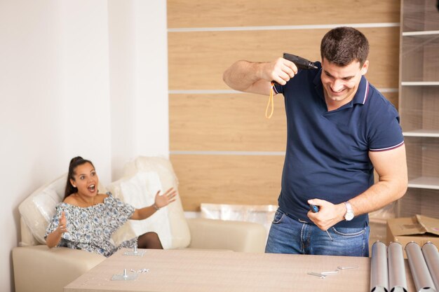 Jovem casal feliz montando móveis de auto-montagem enquanto se mudavam