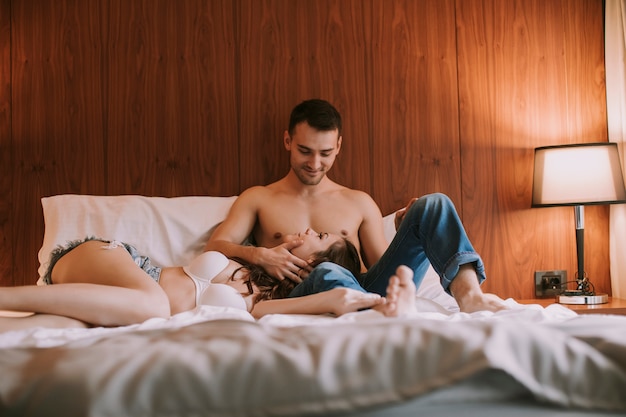 Jovem casal feliz no amor, deitada na cama e amando um ao outro