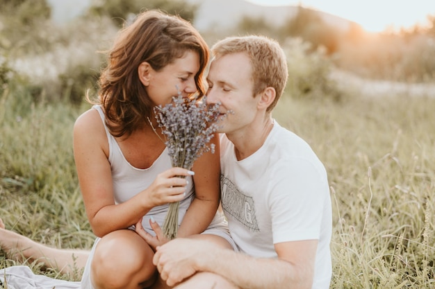 Jovem casal feliz no fundo da natureza. flores cheirando casal. conceito de amor