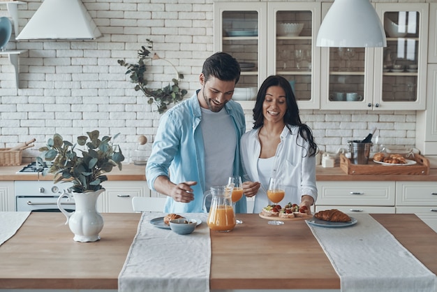 Jovem casal feliz preparando o café da manhã enquanto passa algum tempo na cozinha doméstica