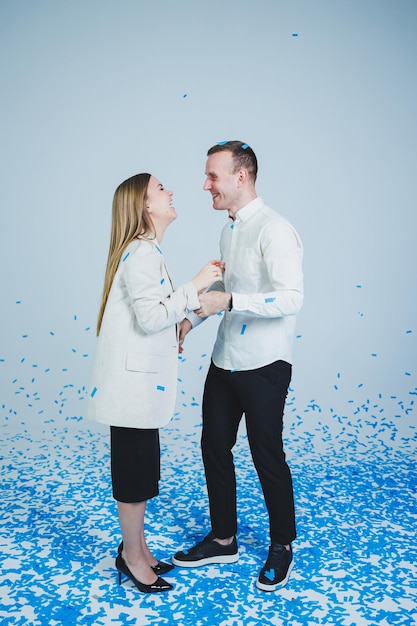Jovem casal feliz se abraçando em confete azul Um casal apaixonado se alegra e se diverte Sessão de fotos de gênero