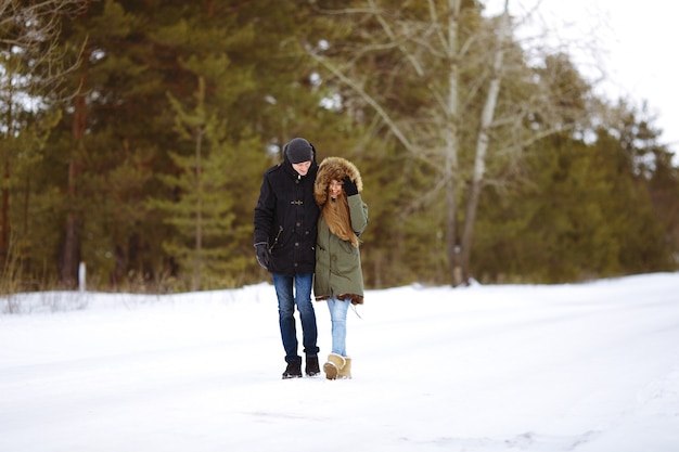 Jovem casal feliz se abraçando na floresta de inverno