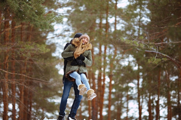 Jovem casal feliz se abraçando na floresta de inverno