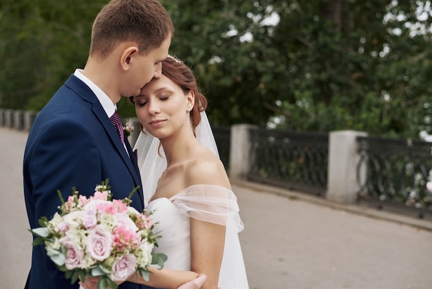 Jovem casal feliz se abraçando no casamento ao ar livre