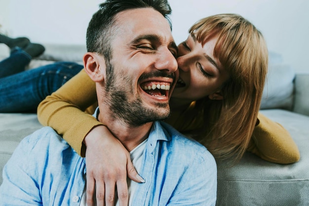 Jovem casal feliz se divertindo conversando rindo e relaxando em casa no sofá