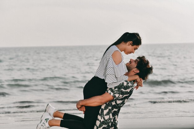 Jovem casal feliz segurando nos braços na praia modelo paquistanês indiano