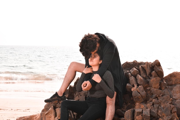 jovem casal feliz sentado na praia modelo paquistanês indiano