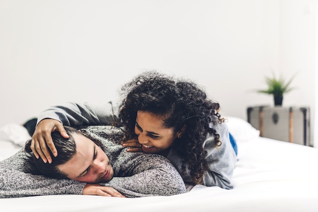 Jovem casal feliz sorrir e se divertir deitado na cama juntos em casa