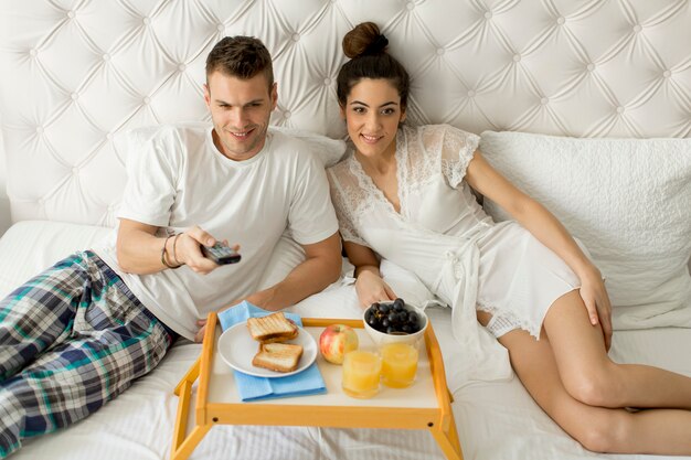 Jovem casal feliz tomando café da manhã no quarto de luxo