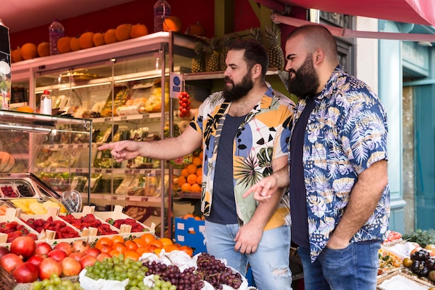 Jovem casal gay comprando frutas no mercado ao ar livre Conceito de estilo de vida saudável