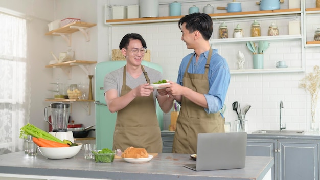 Jovem casal gay sorridente cozinhando juntos na cozinha em casa LGBTQ e conceito de diversidade