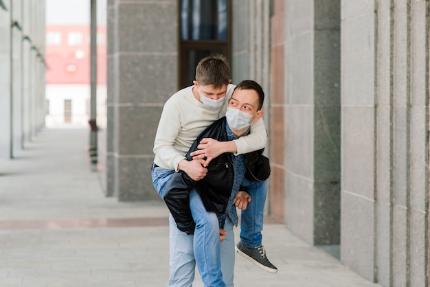 Jovem casal gay usando máscara médica, abraçando a cidade.