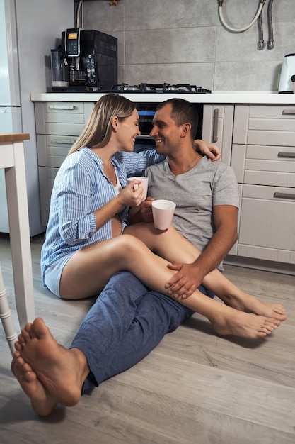 Jovem casal grávida na cozinha no chão