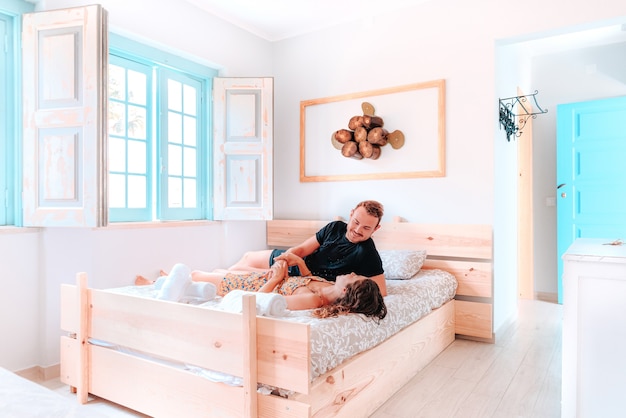 Jovem casal heterossexual branco deitado em uma cama de hotel iluminada à luz do dia