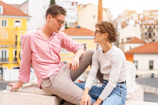 Jovem casal hipster lindo em óculos de sol apaixonados sentado escadas na rua da cidade velha