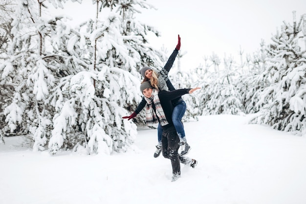 Jovem casal homem caucasiano e mulher cavalgando nas férias de inverno em floresta nevada