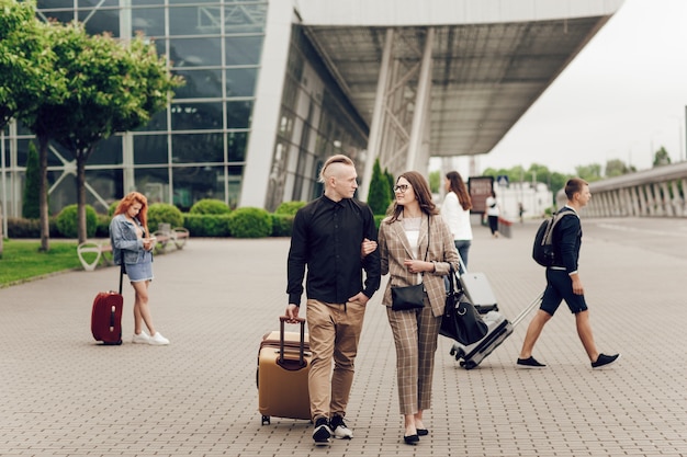 Jovem casal, homem e mulher perto do aeroporto com uma mala