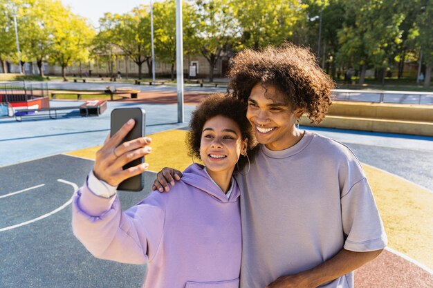 Jovem casal inter-racial namorando ao ar livre, meio urbano moderno e colorido - Pessoas multiétnicas com roupas urbanas elegantes e descoladas se unindo ao ar livre