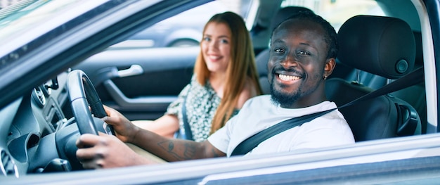 Jovem casal interracial sorrindo feliz no carro