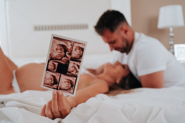 Foto jovem casal irreconhecível, olhando um para o outro e sorrindo. em primeiro plano, o ultrassom do bebê.