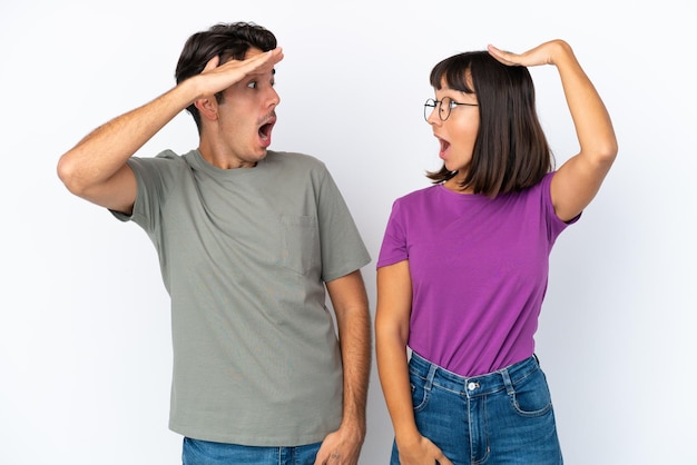 Jovem casal isolado em fundo branco isolado com surpresa e expressão facial chocada