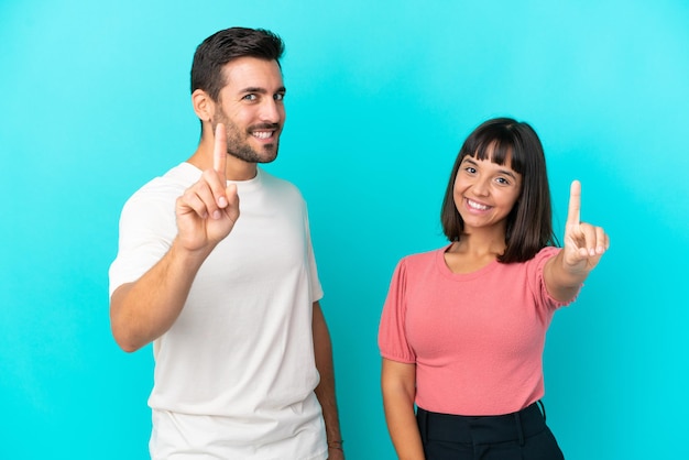 Foto jovem casal isolado em um fundo azul, mostrando e levantando um dedo