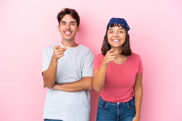 Jovem casal isolado no fundo rosa aponta o dedo para você com uma expressão confiante