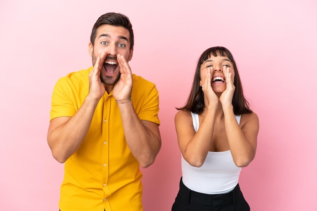 Foto jovem casal isolado no fundo rosa gritando e anunciando algo