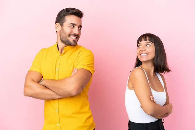 Jovem casal isolado no fundo rosa olhando por cima do ombro com um sorriso