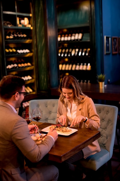 Jovem casal jantando no restaurante e bebendo vinho tinto