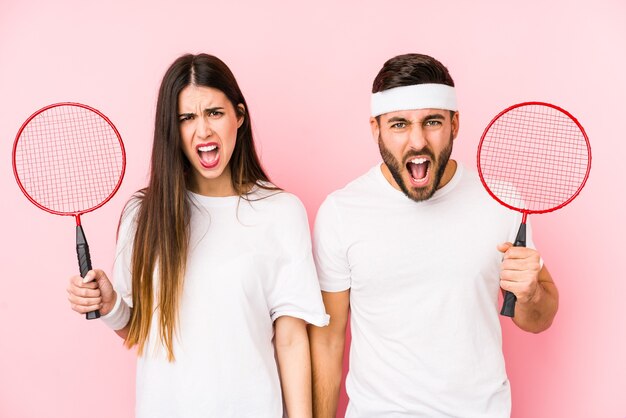 Jovem casal jogando badminton isolado gritando muito zangado e agressivo.