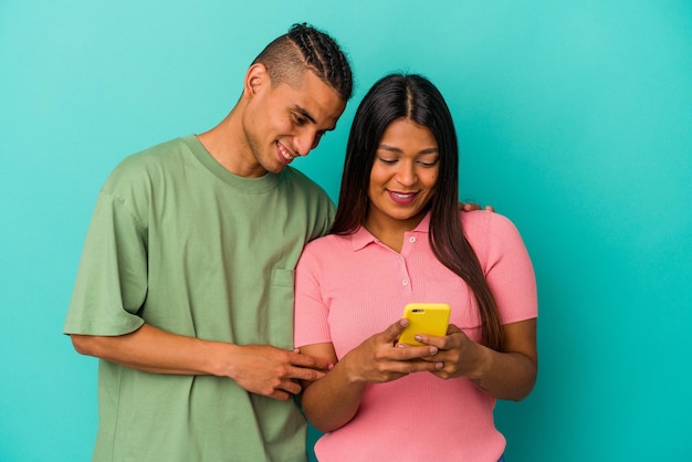 Jovem casal latino com um telefone celular isolado em fundo azul