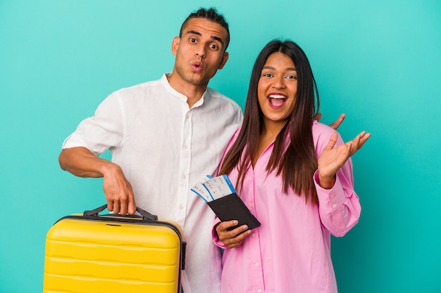 Jovem casal latino vai viajar isolado em um fundo azul surpreso e chocado.